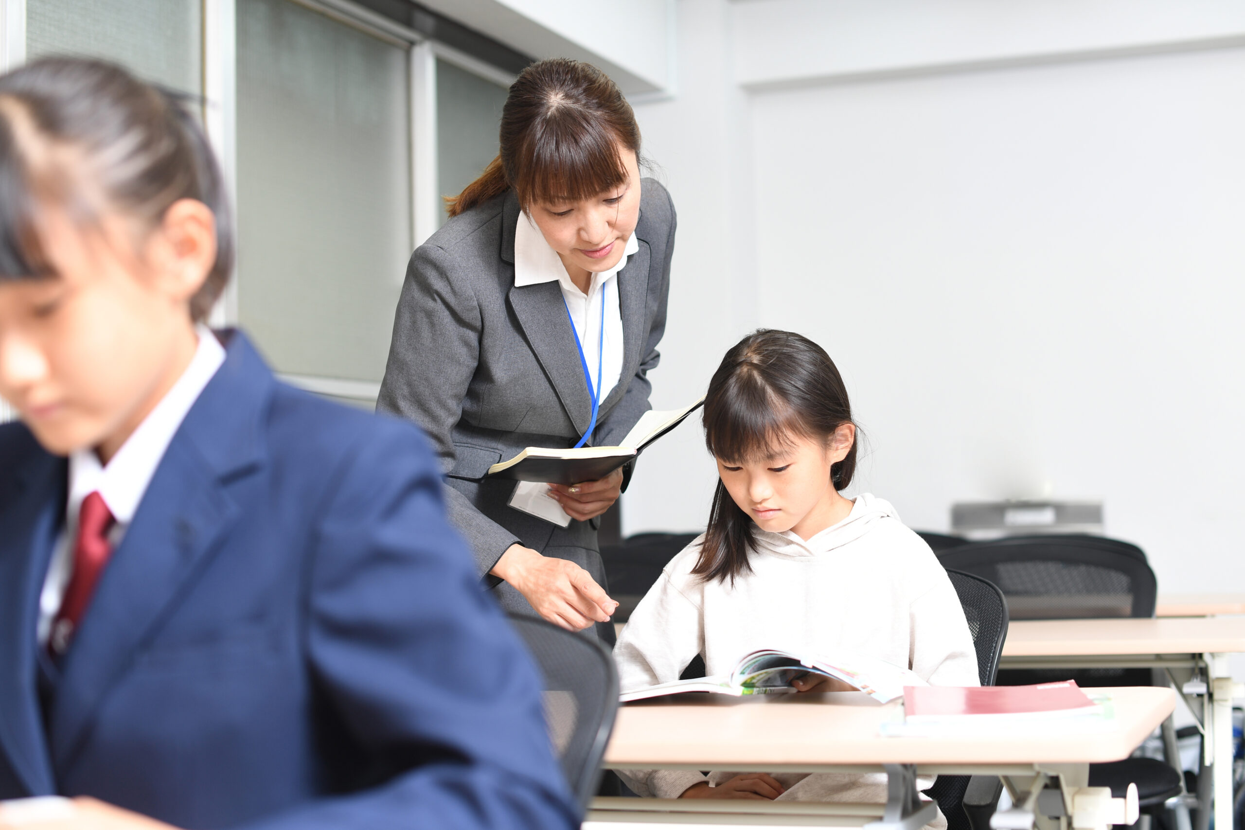 授業中に勉強をする女子学生と塾講師のイメージ